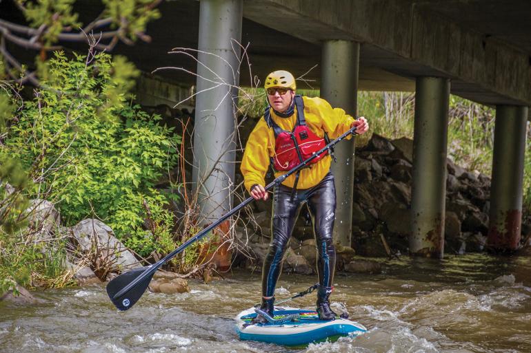 Paddleboarder on small creek, spring runoff