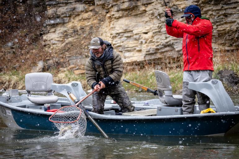 Fly fishermen netting a trout in a snowstorm