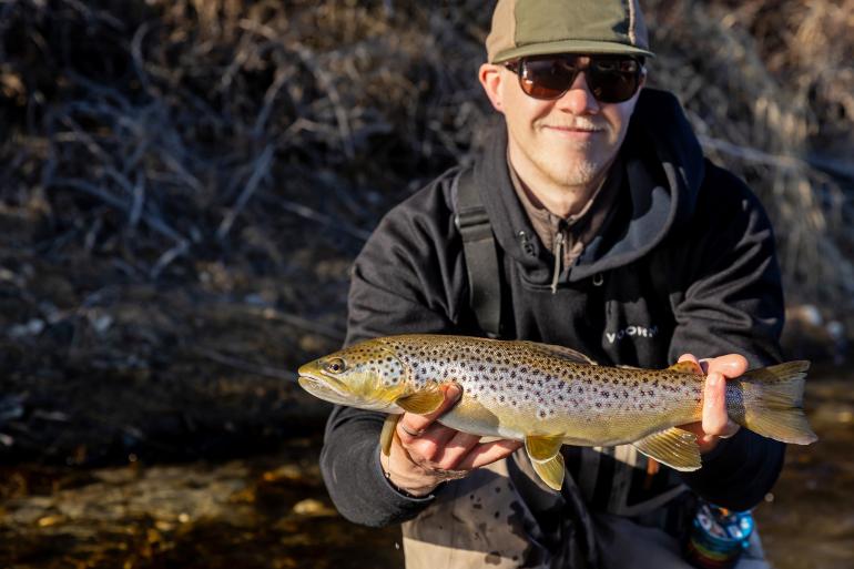 Fly fisherman holding brown trout