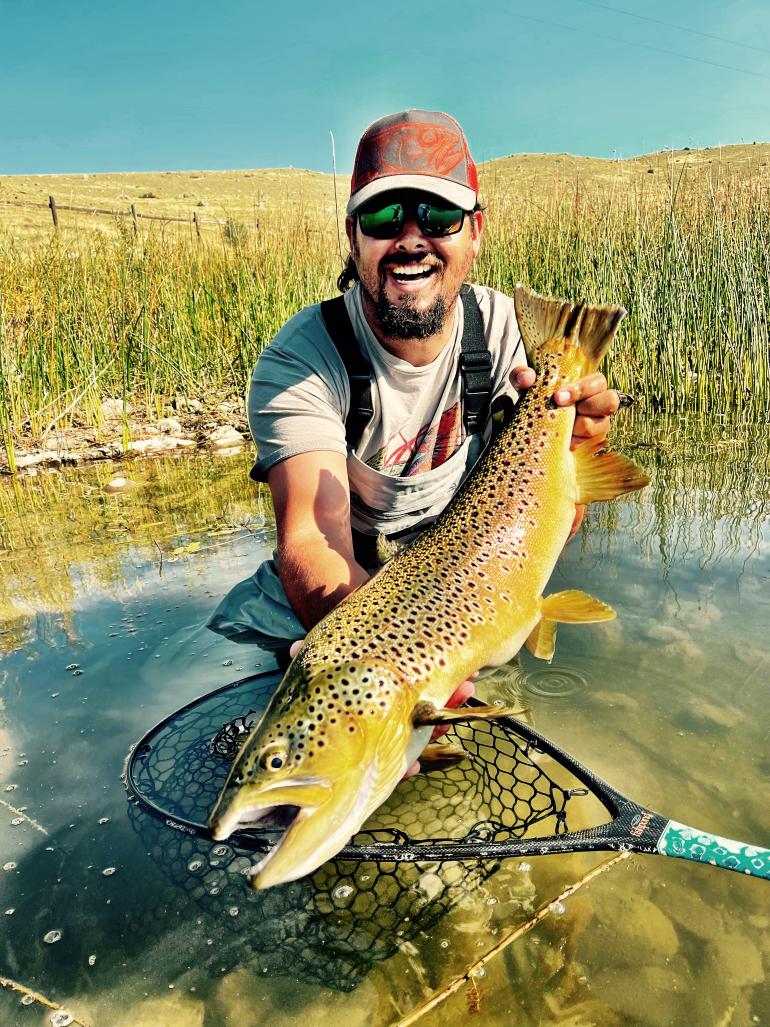 Artist Derek DeYoung holding a brown trout