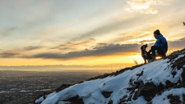 Man with dog on mountain at sunset